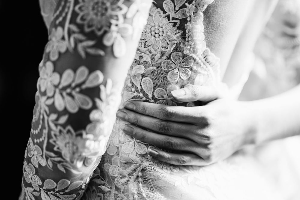 Black and white closeup of hands gently touching fabric with delicate floral patterns.