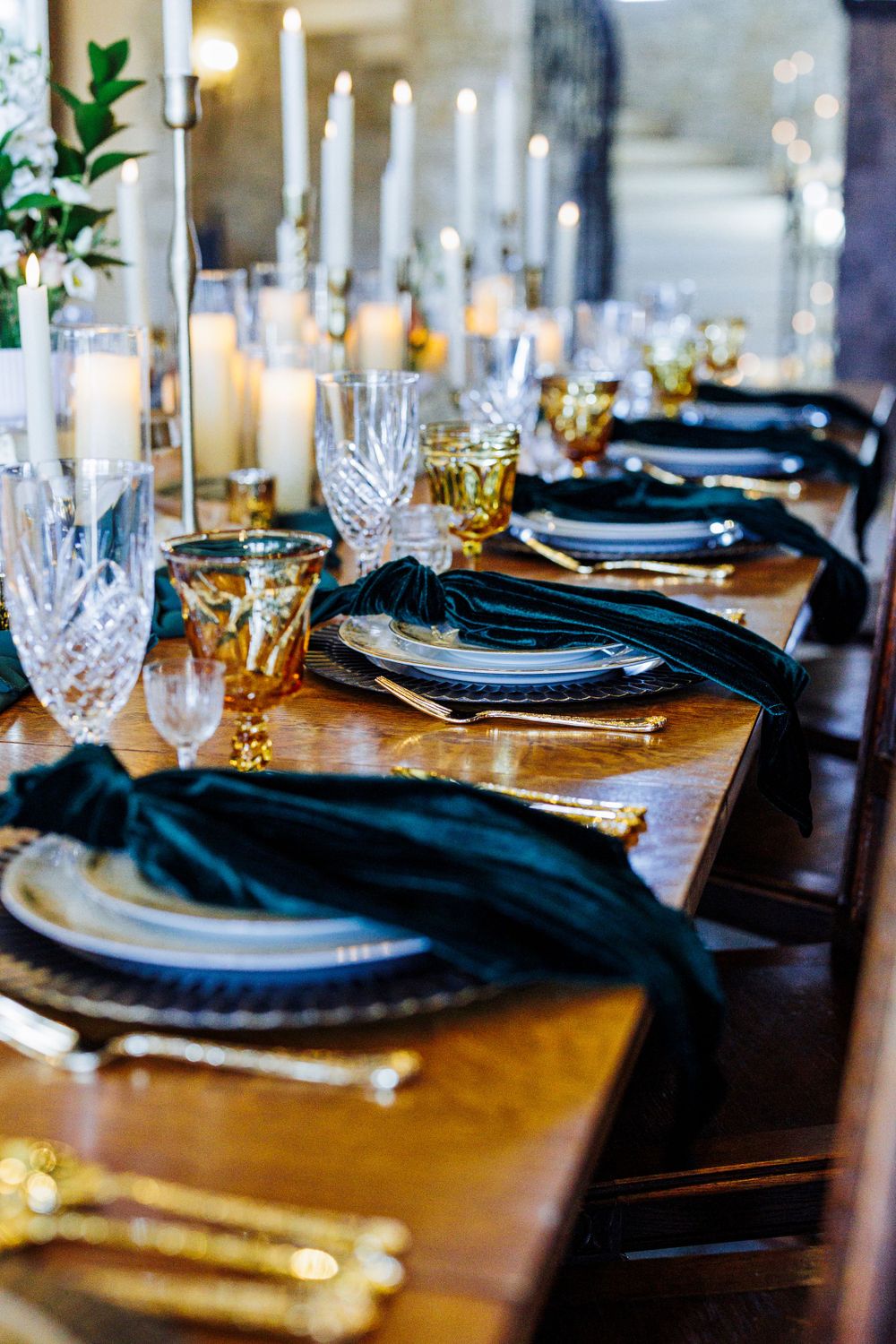 Elegant table setting with crystal glassware, black napkins, and gold accents on wooden surface for formal dining.