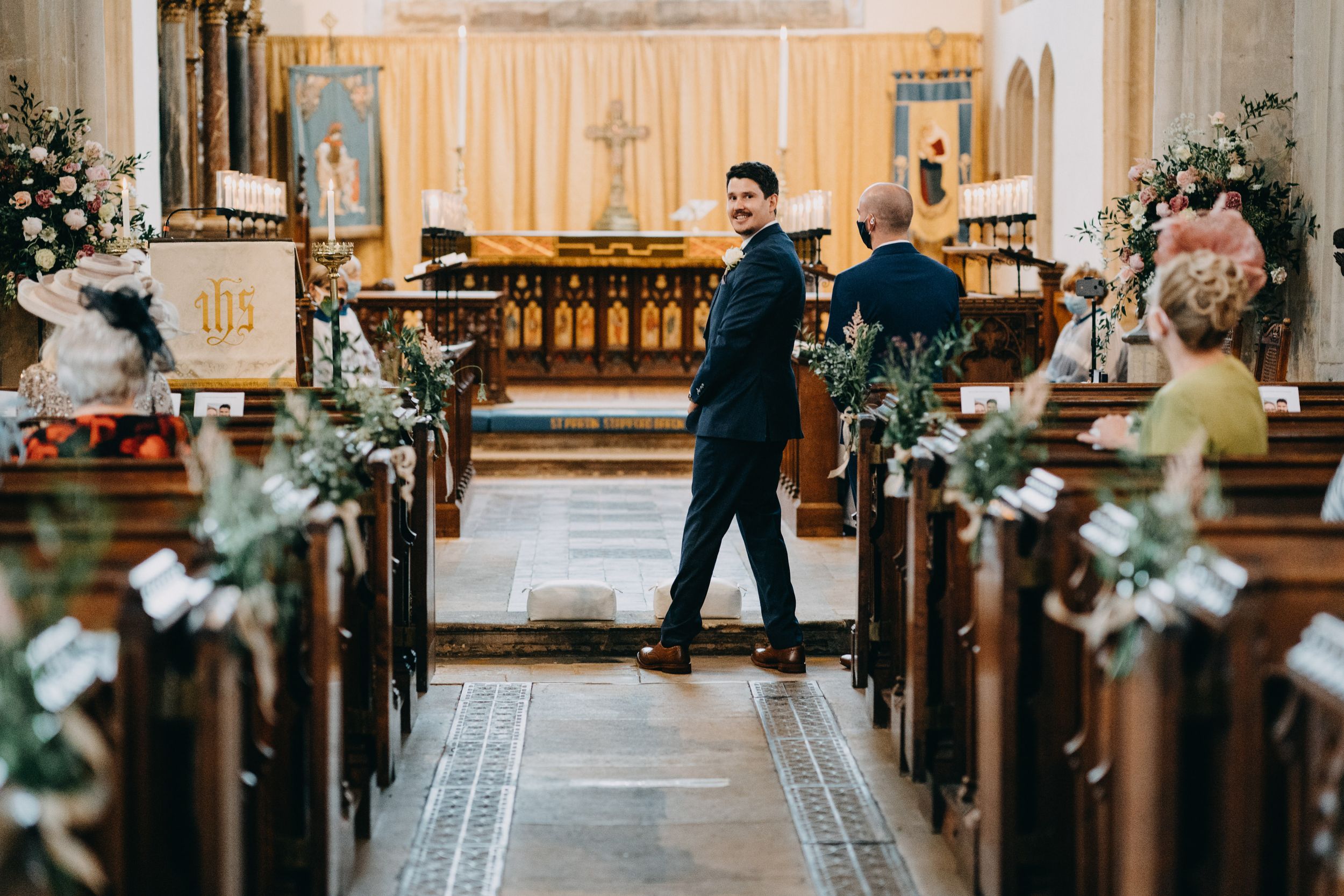 Elegant church interior decorated with floral arrangements and greenery along wooden pews for a wedding ceremony.