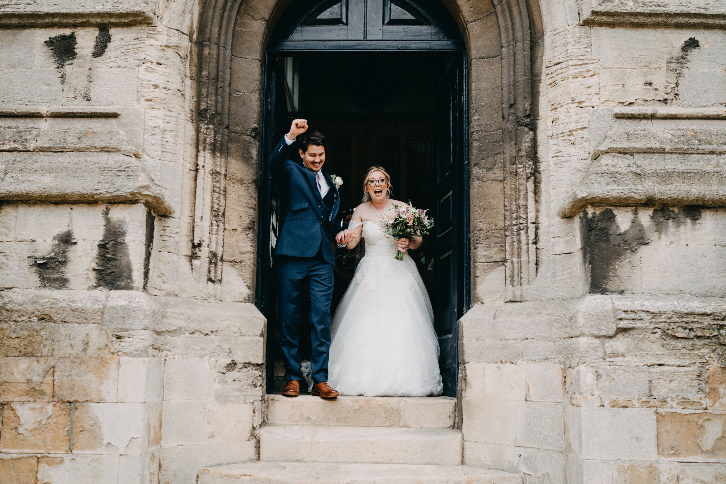 A bride and groom stand together in a historic stone church doorway during their wedding celebration in Stamford.