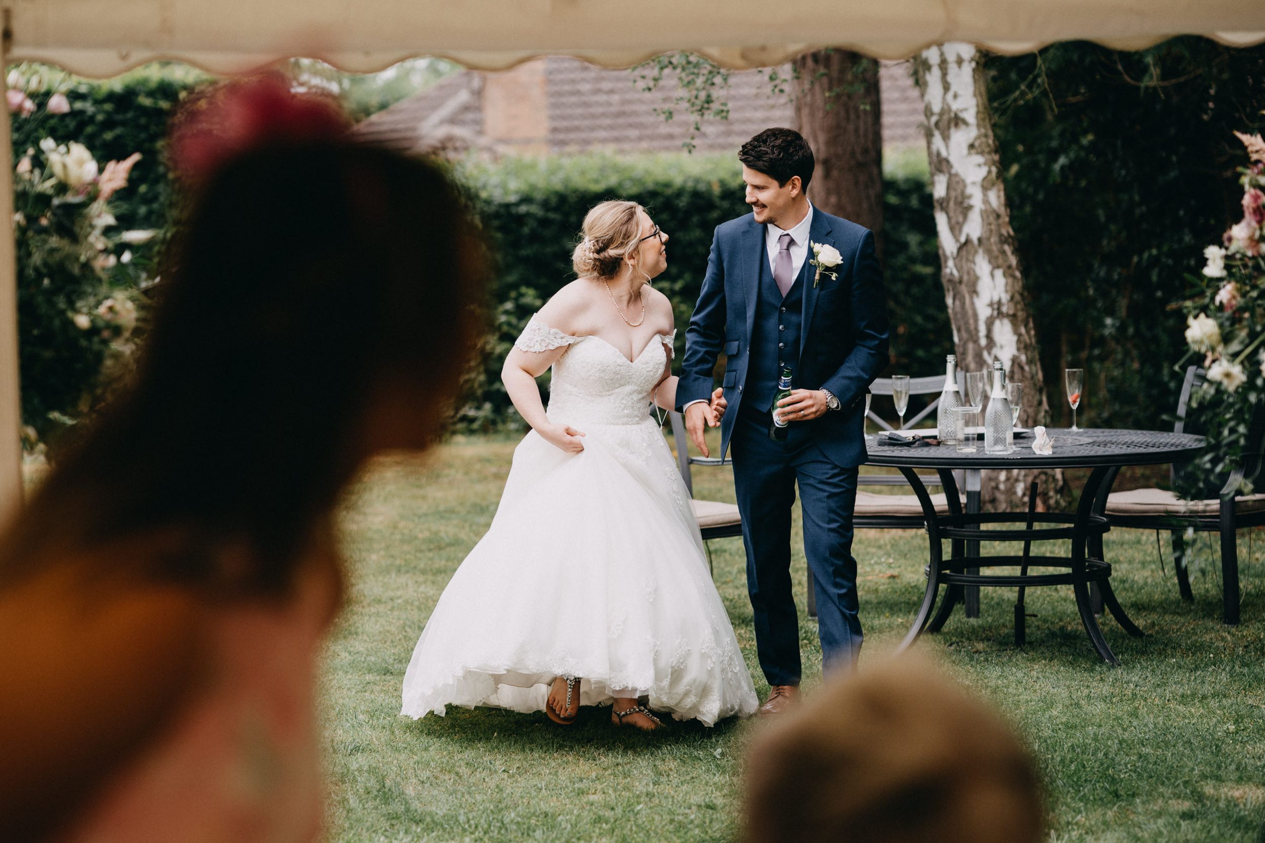 A couple sharing a romantic moment in a garden setting on their wedding day wearing formal white dress and navy suit.