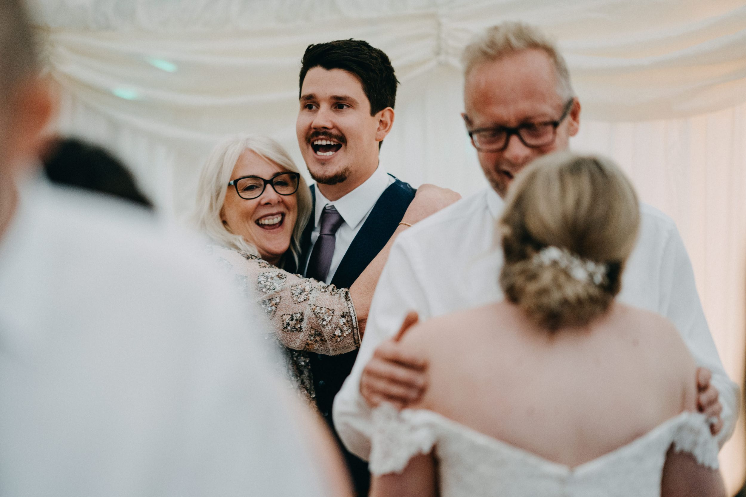 Candid moment of joyful laughter shared between wedding guests during an indoor celebration.
