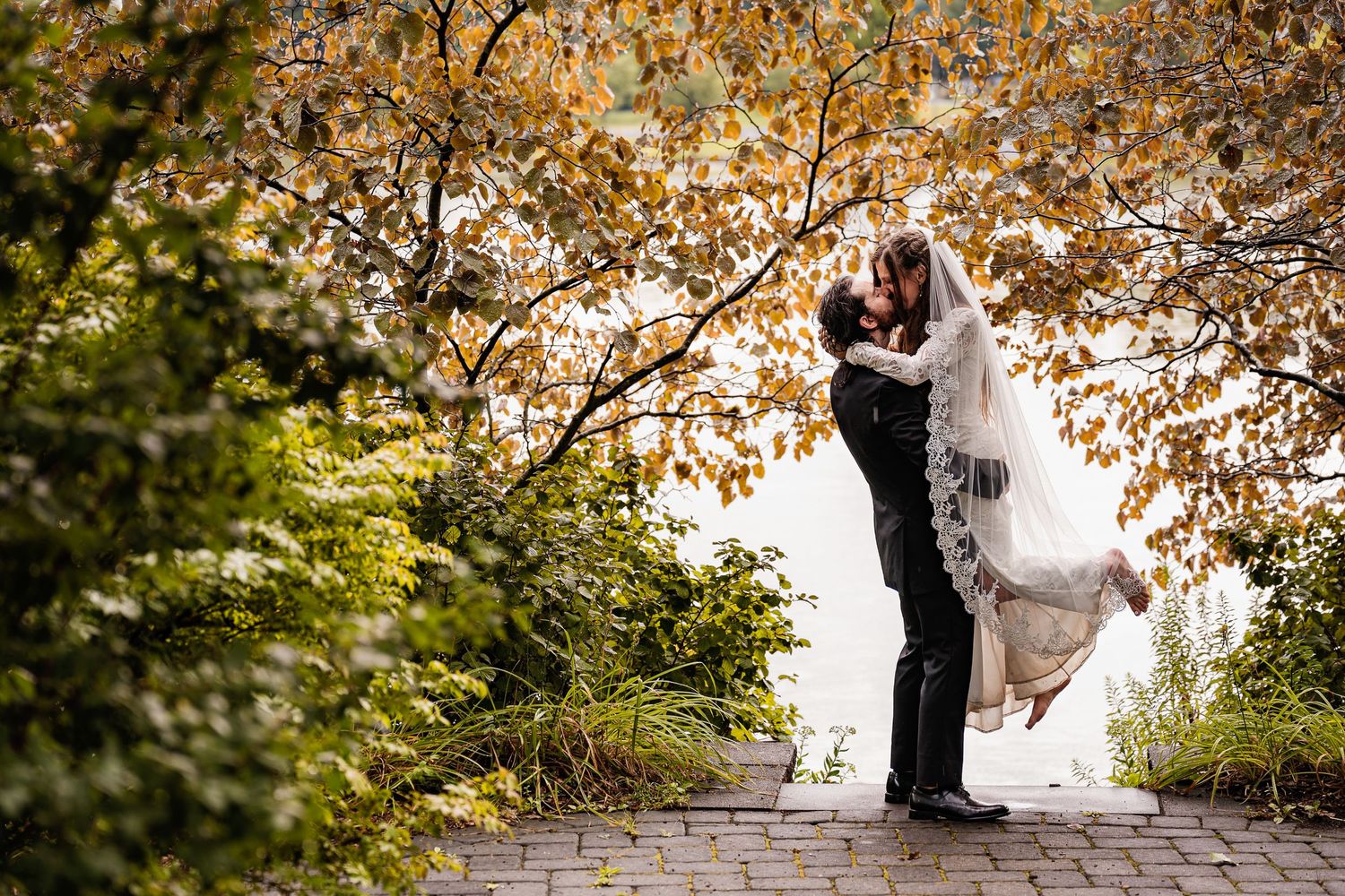 A romantic wedding moment captured under golden autumn trees.