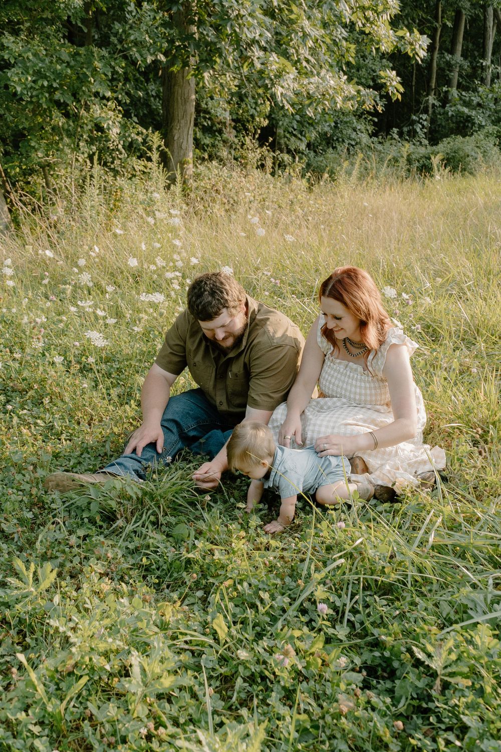 Couple sitting in summer meadow with wildflowers on a sunny day.