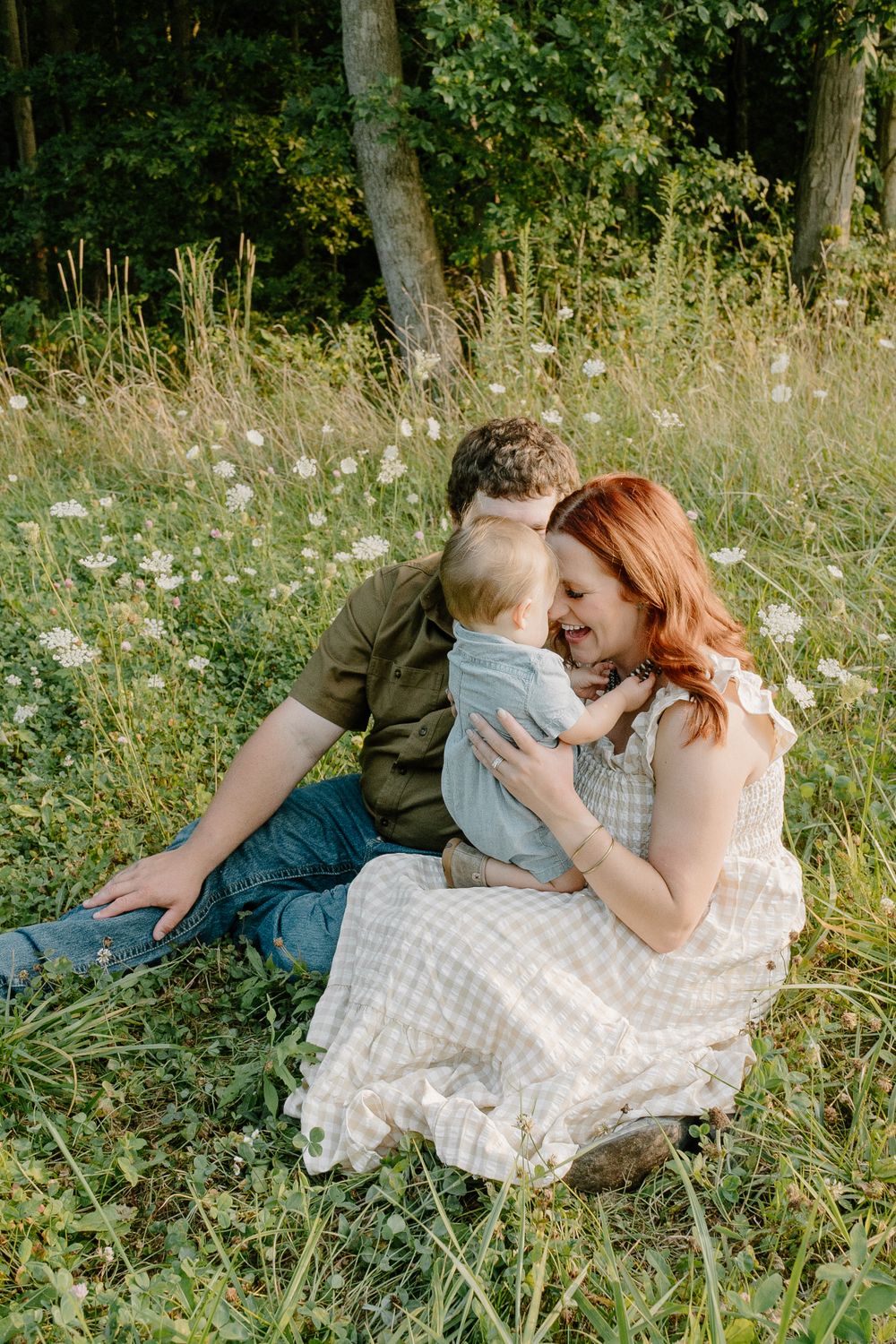 Family sharing intimate moment while sitting in summer meadow with wildflowers.