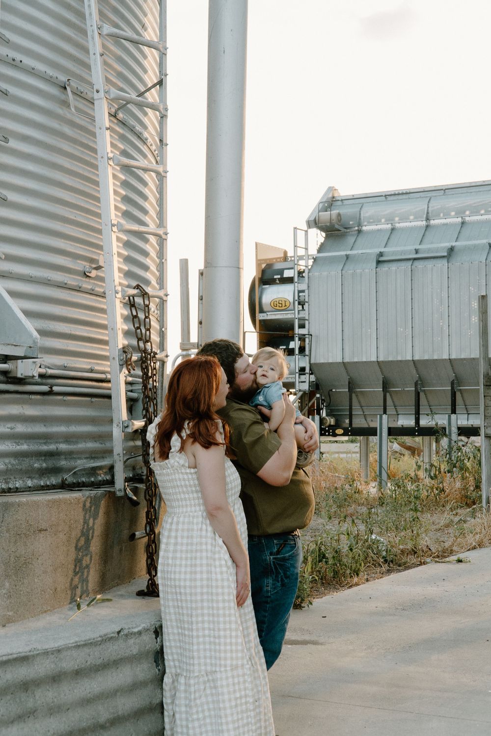 Intimate family moment captured against industrial agriculture backdrop.