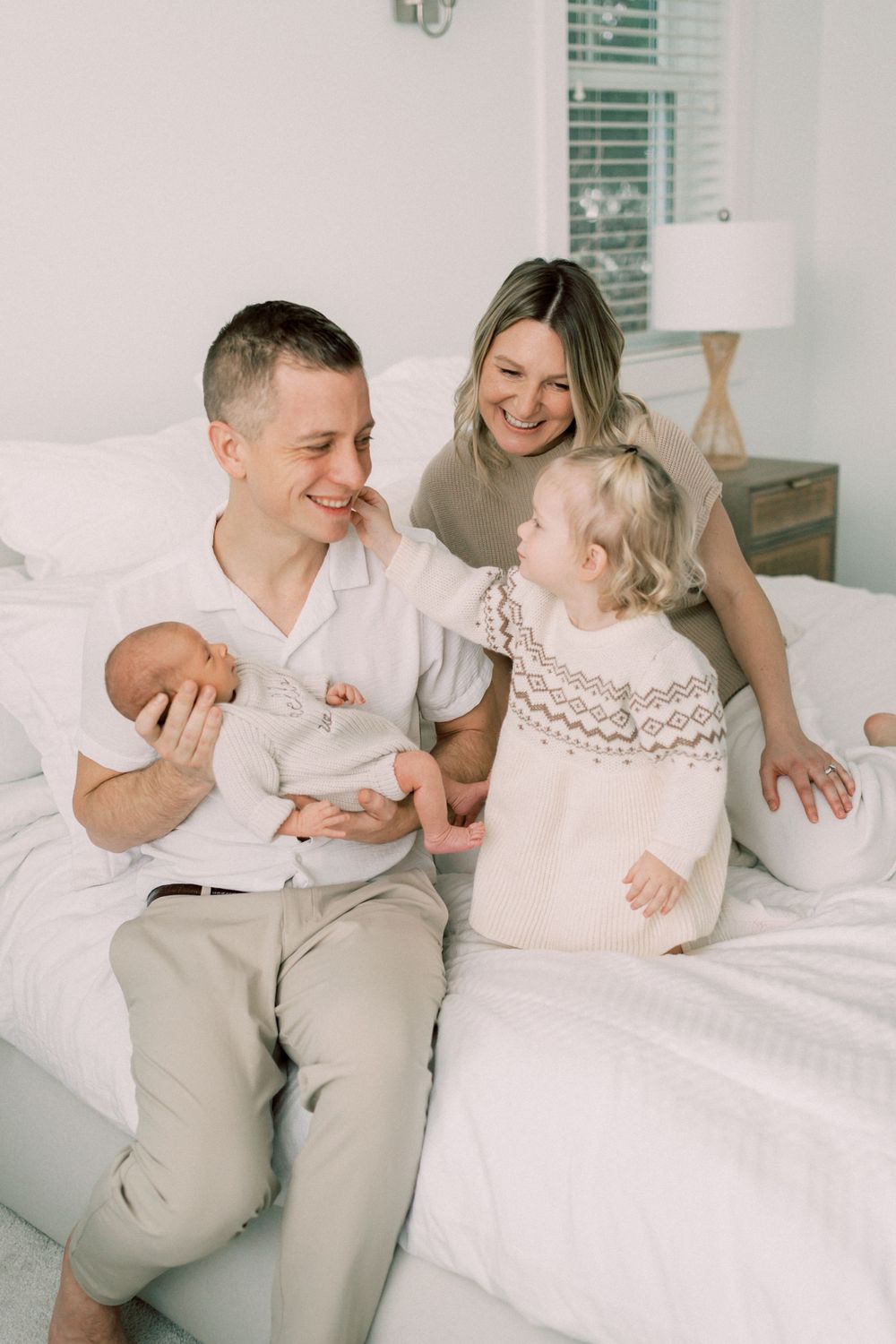 A family shares a joyful moment together on a white bed.