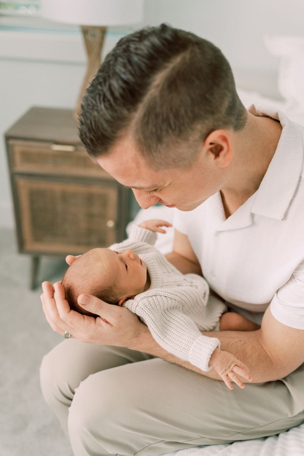 An intimate moment between a caregiver and newborn baby in white knit clothing.