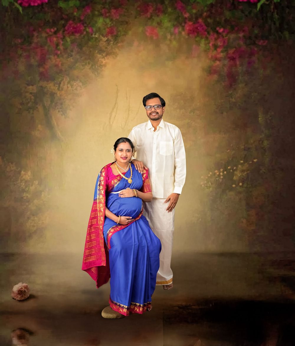 Maternity portrait with couple in traditional Indian attire against floral backdrop.
