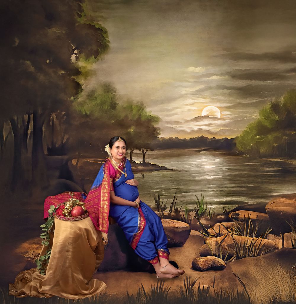 Maternity photo in blue saree against evening lakeside backdrop.