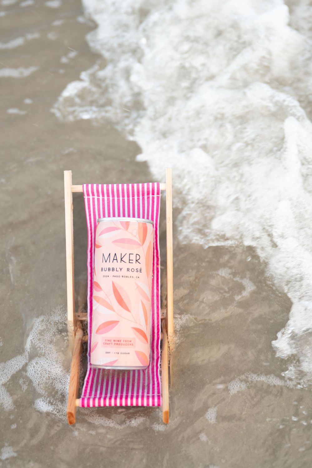 Four sequential photos show a pink striped beach chair with a Maker's horoscope pack against a foamy ocean wave backdrop.