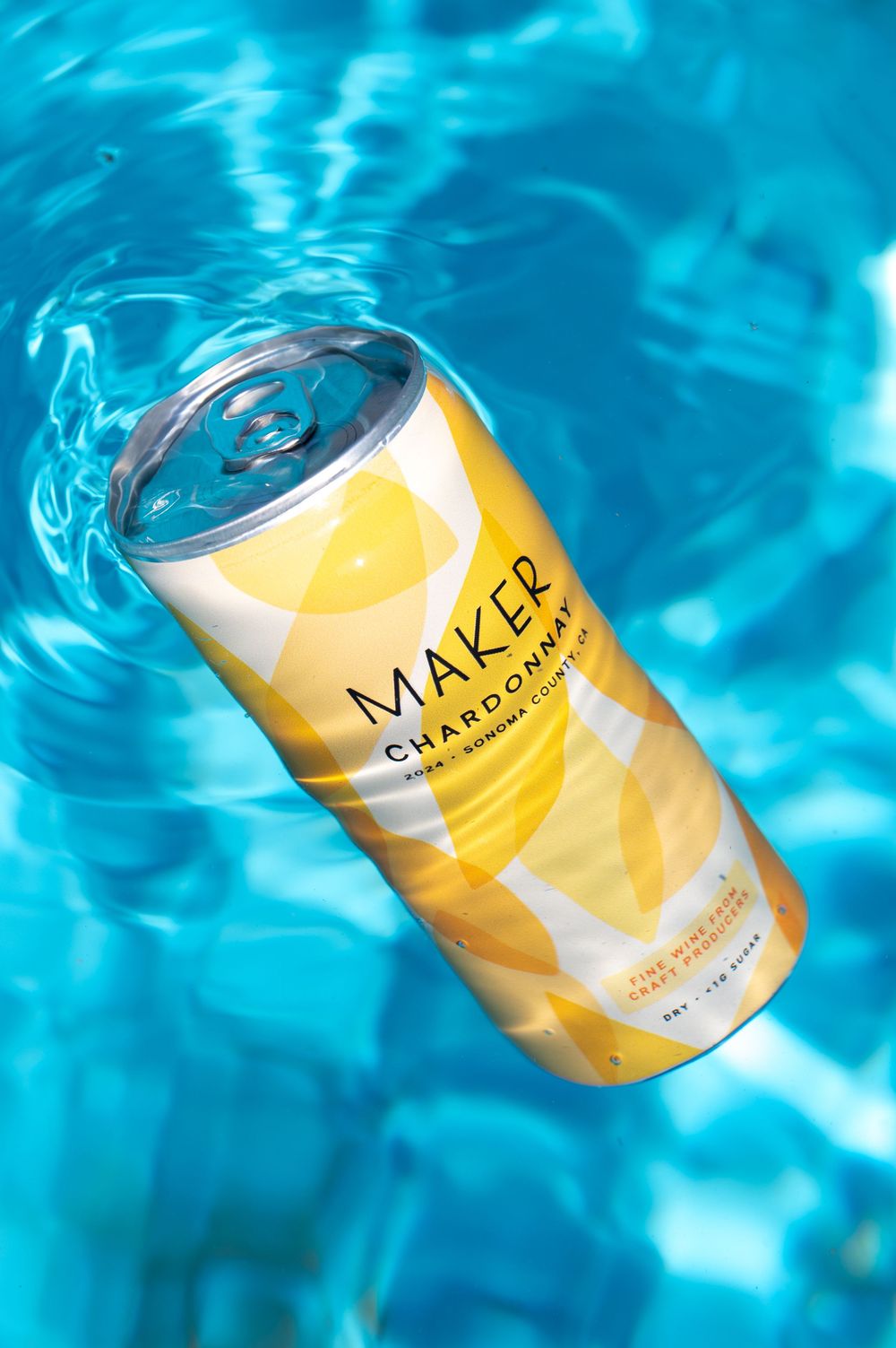 Four sequentially shot images of a yellow and white beverage can floating in rippling blue pool water.