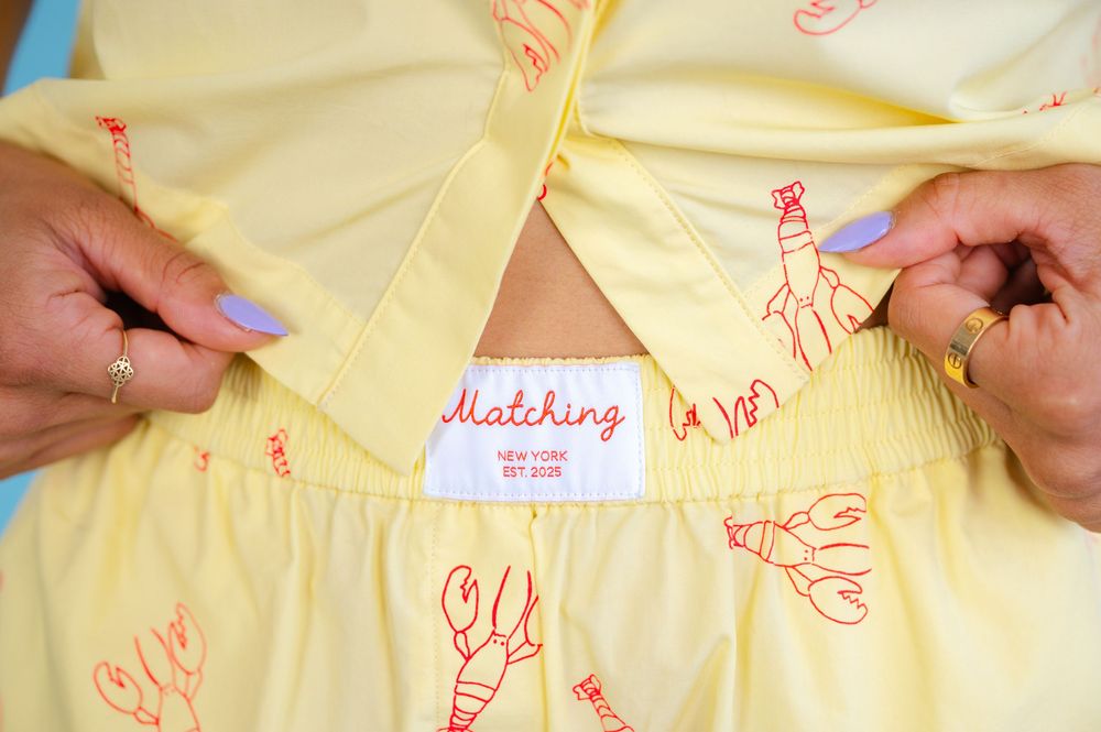 Hand draws a red line pattern on light yellow fabric with a marker in multiple steps.