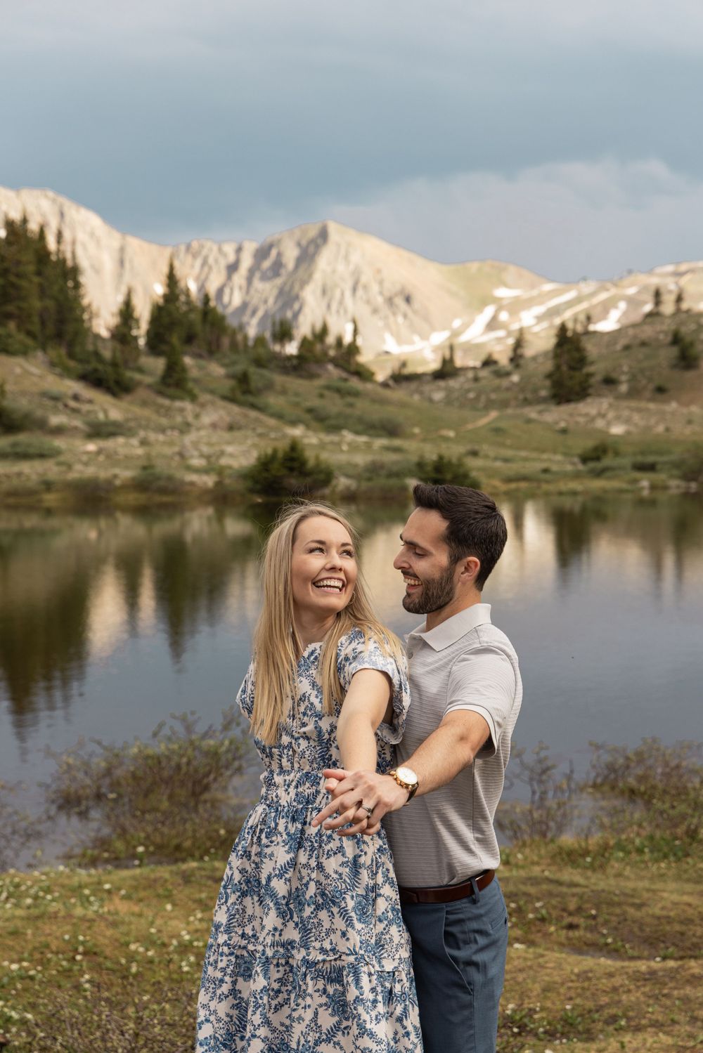 A couple shares an intimate moment by an alpine lake surrounded by majestic mountain peaks at Loveland Pass, Colorado..