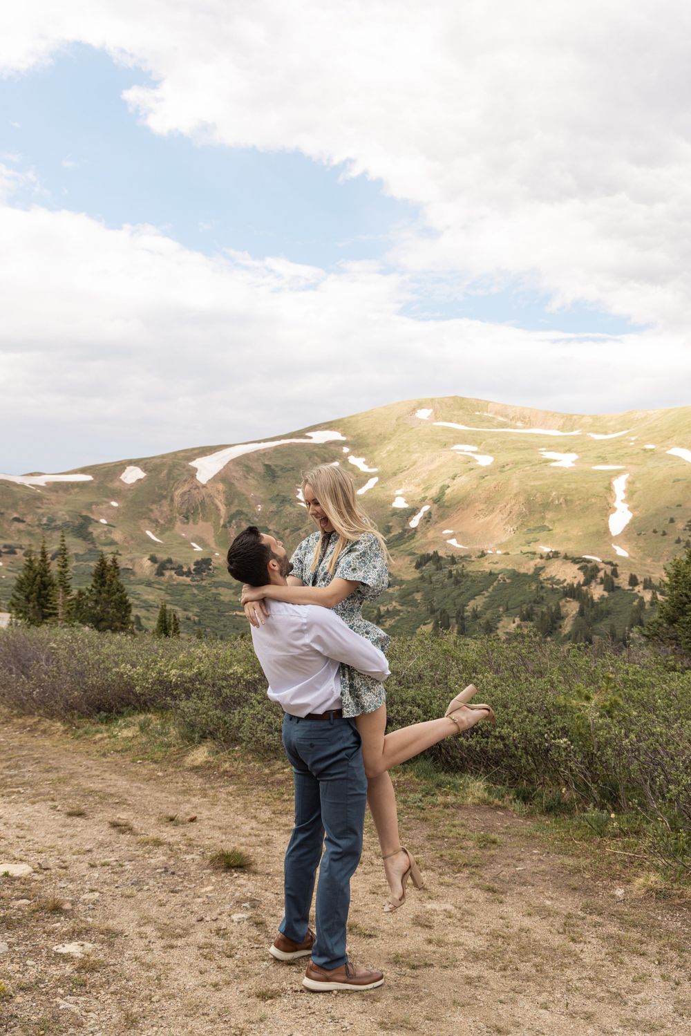 A romantic dance scene unfolds against a backdrop of snow-dusted mountain peaks and wildflowers.