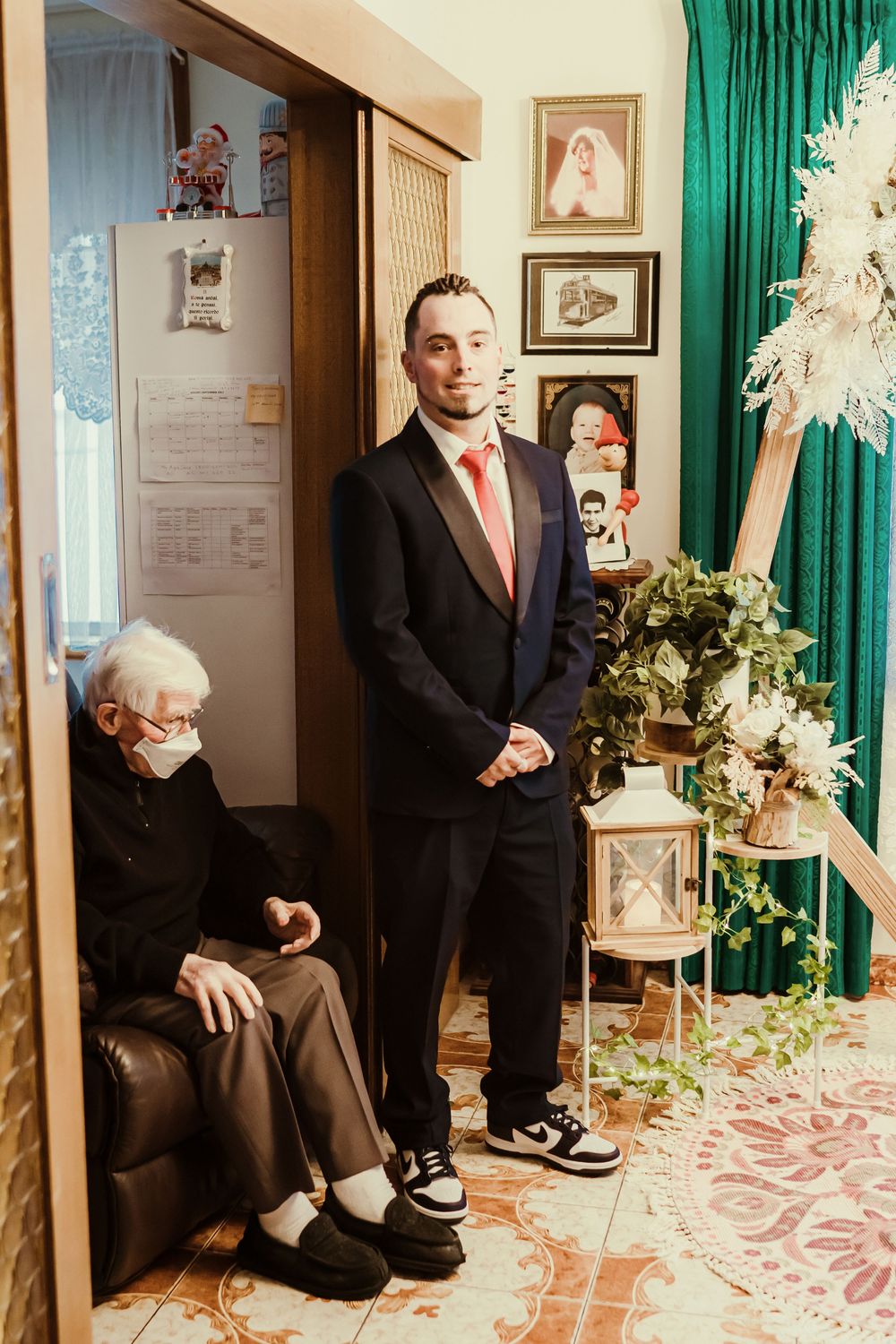 A formal gathering in a vintage-styled room with emerald curtains, ornate decor, and patterned floors.