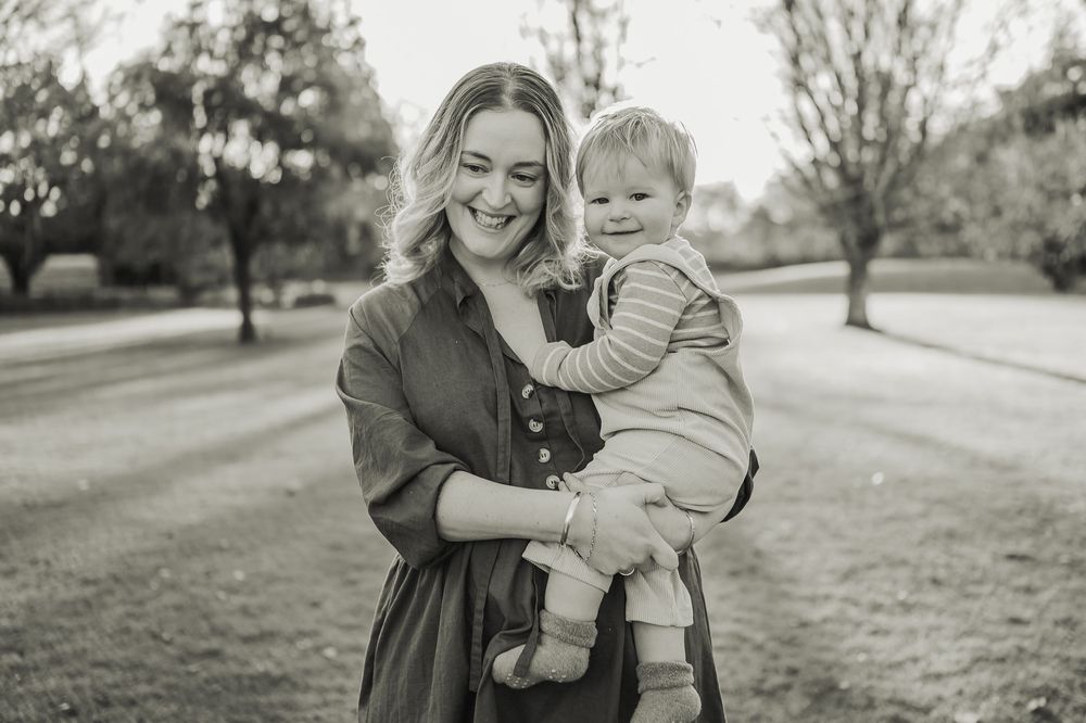 A candid black and white photography series showing tender moments between parent and child in an outdoor park setting.