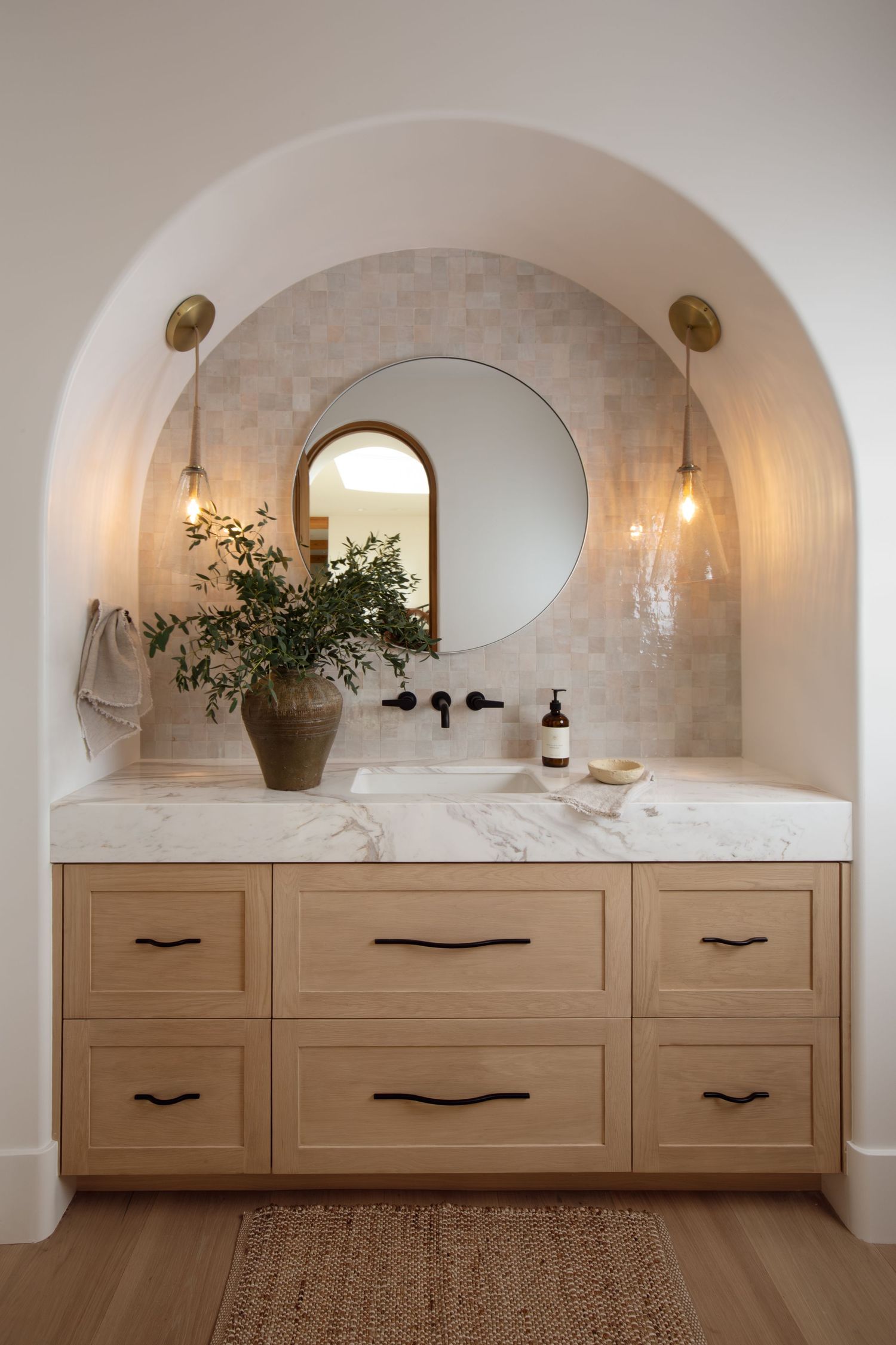 Modern farmhouse kitchen with white marble counters, beige cabinetry, and contemporary dome pendant lights in a warm design.