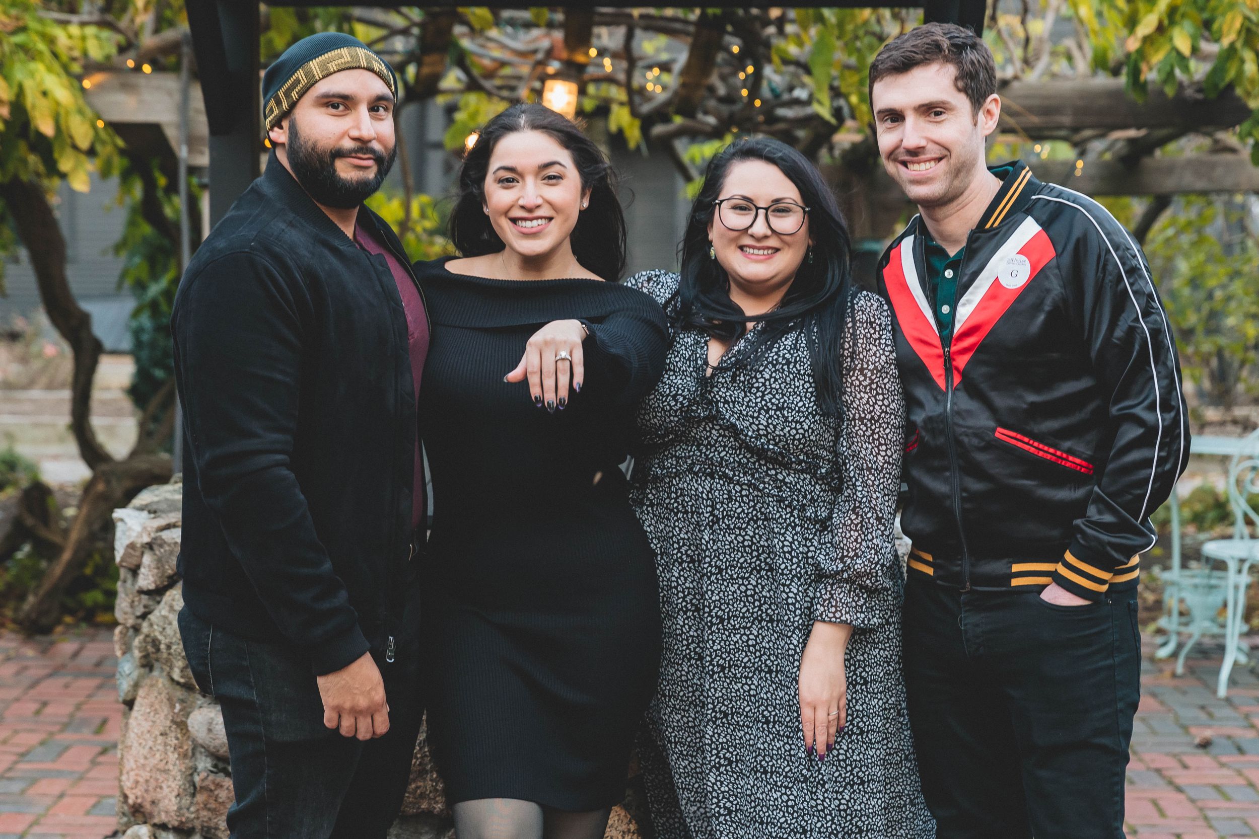 A small group poses together outdoors for a casual family photo against greenery.