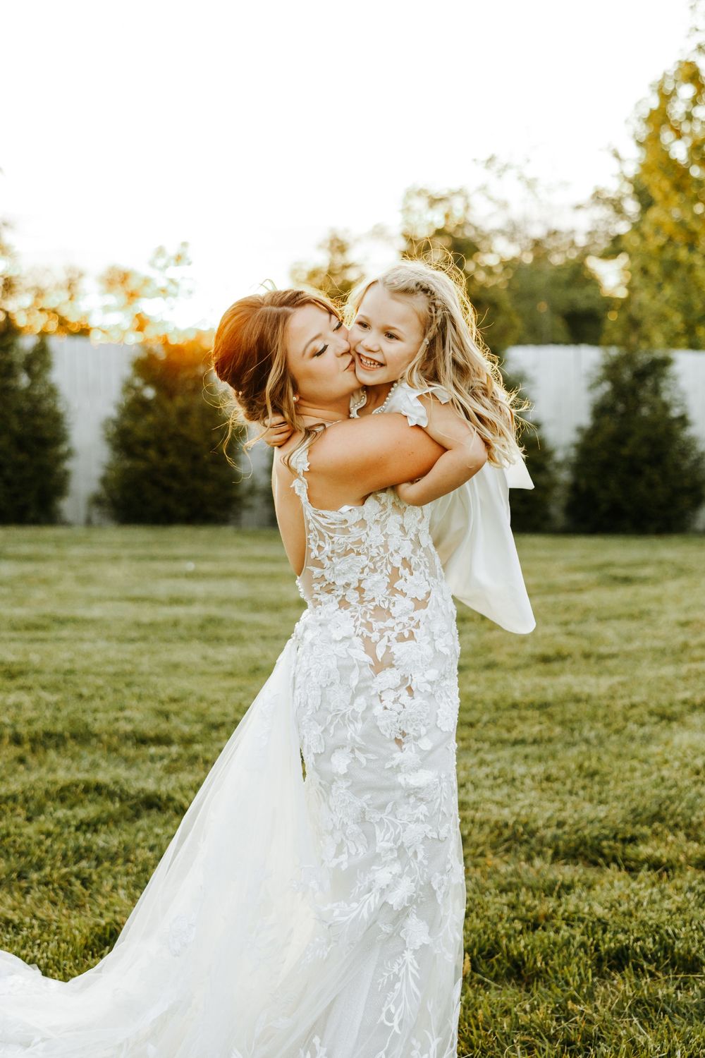 A series of candid moments show a small child being lifted and hugged in a grassy outdoor setting at sunset.