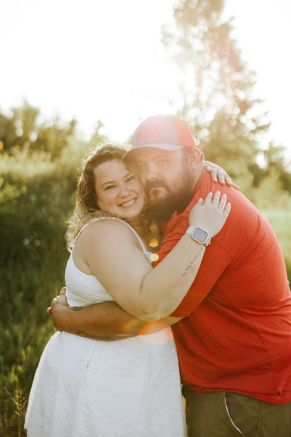 Happy couple embraces and shares laughter during their outdoor sunset engagement photo session.