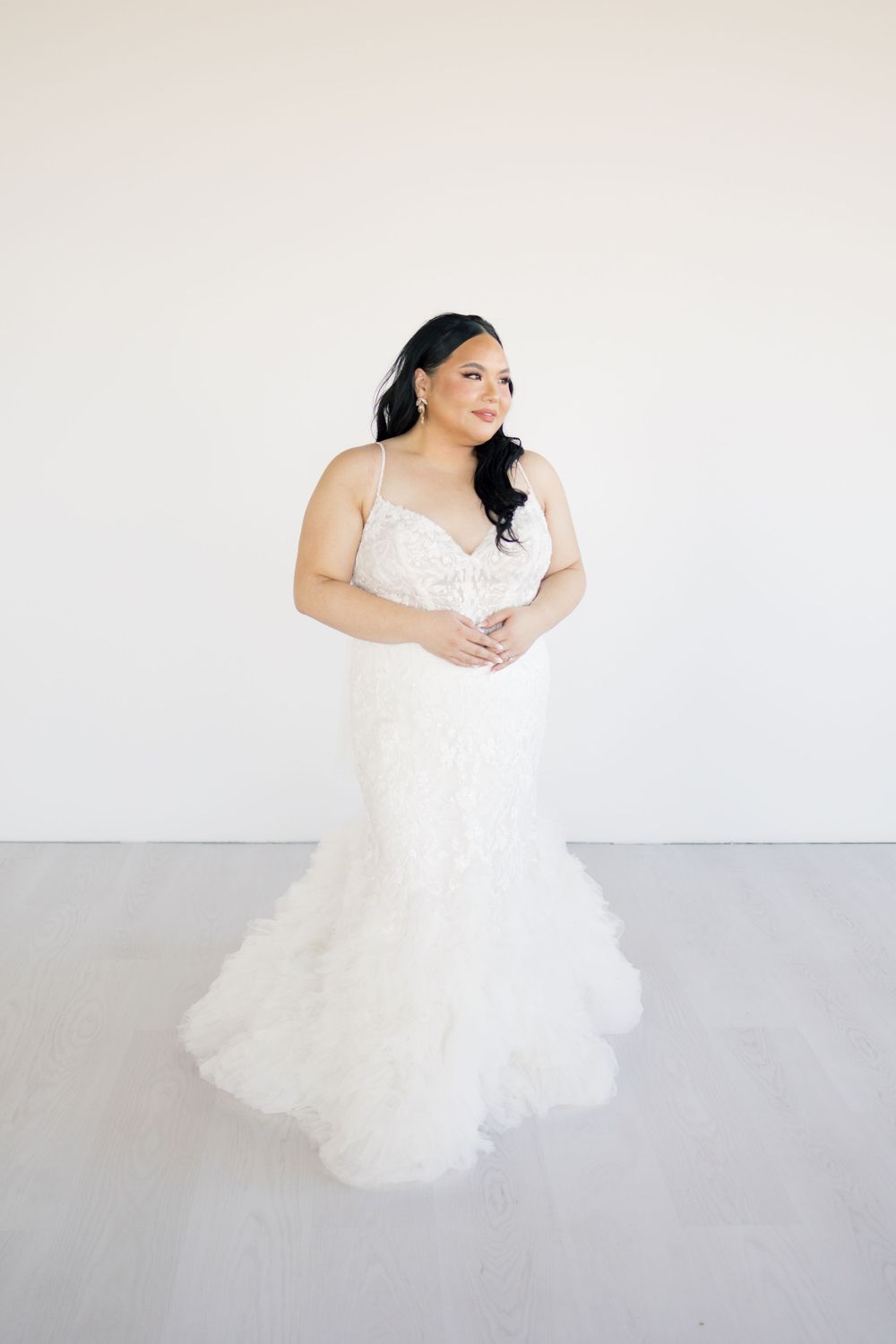 Elegant bridal portrait against minimal white background showing full lace wedding gown.