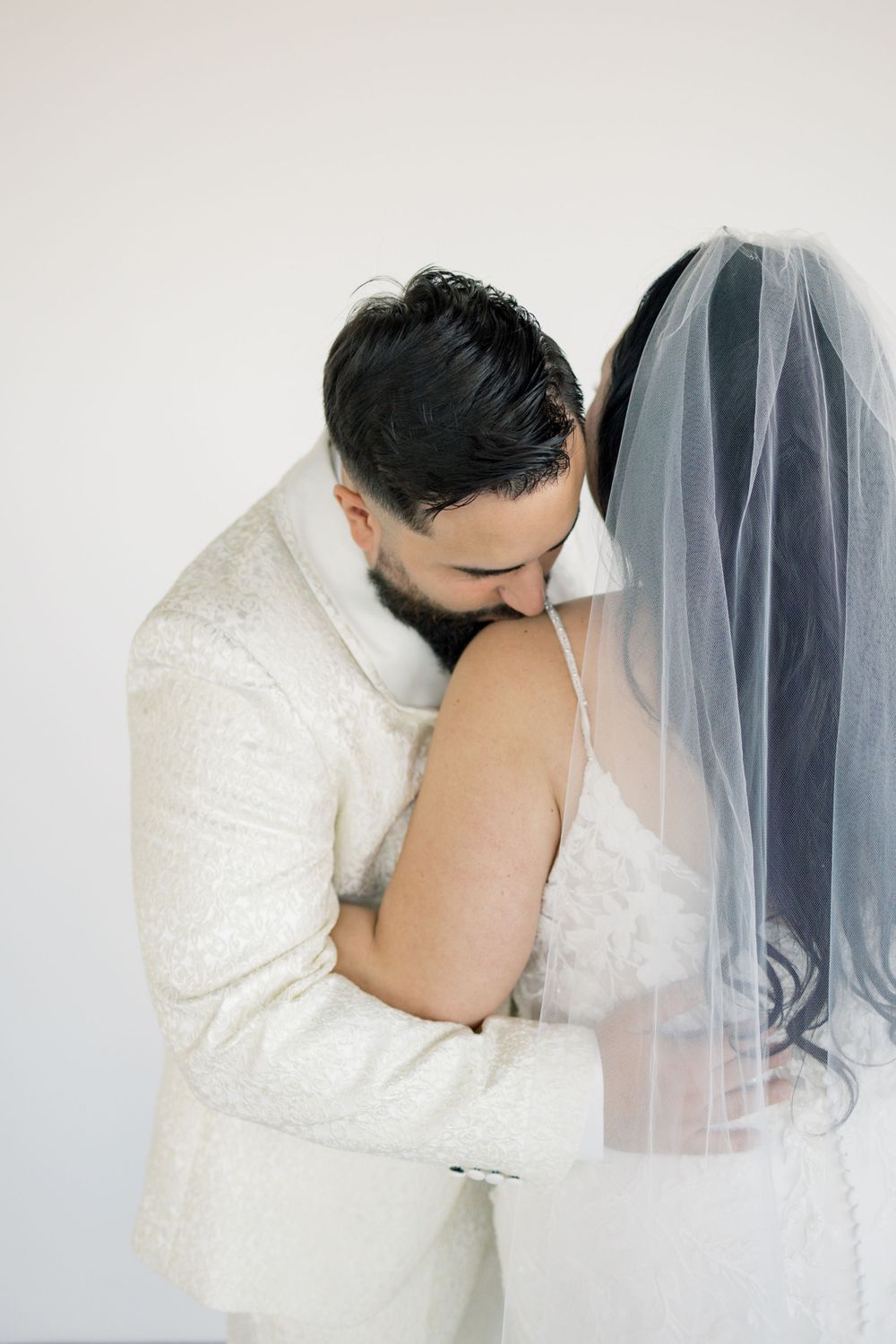 Intimate black and white portrait of groom embracing bride from behind.