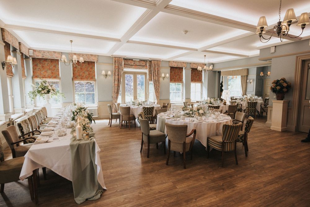 Elegant banquet hall with white-clothed tables, ornate chandeliers, and exposed wooden beams at Washingborough Hall.
