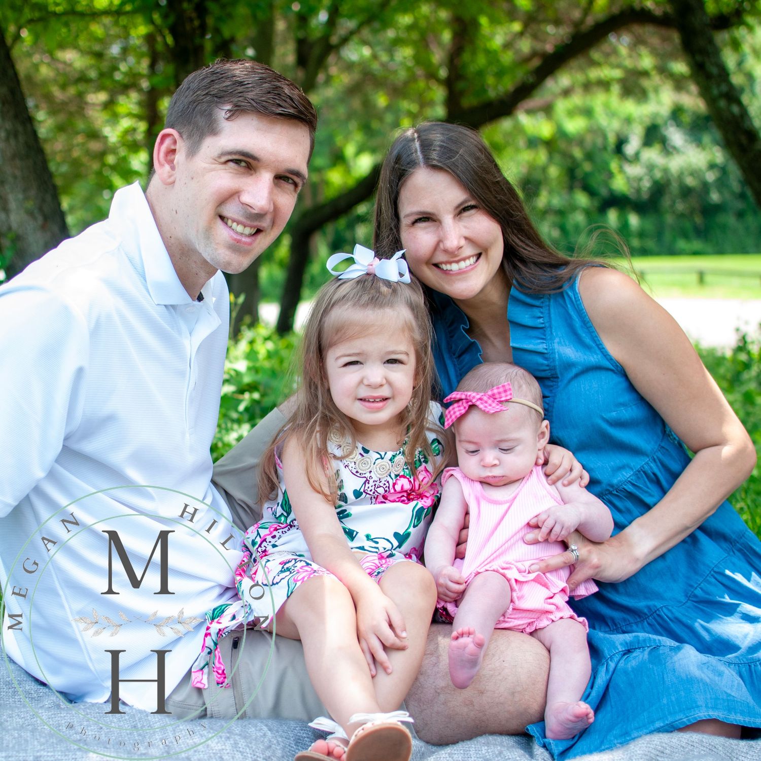 Happy family sitting together outdoors on a sunny day with a natural scene in background.