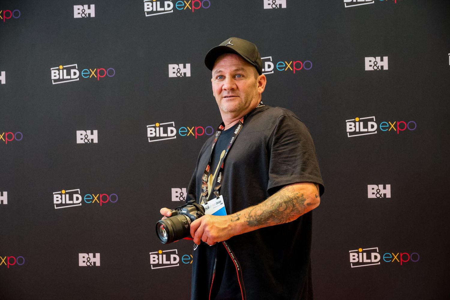 Person stands in front of black backdrop with repeating BILD EXPO logos at a press event.