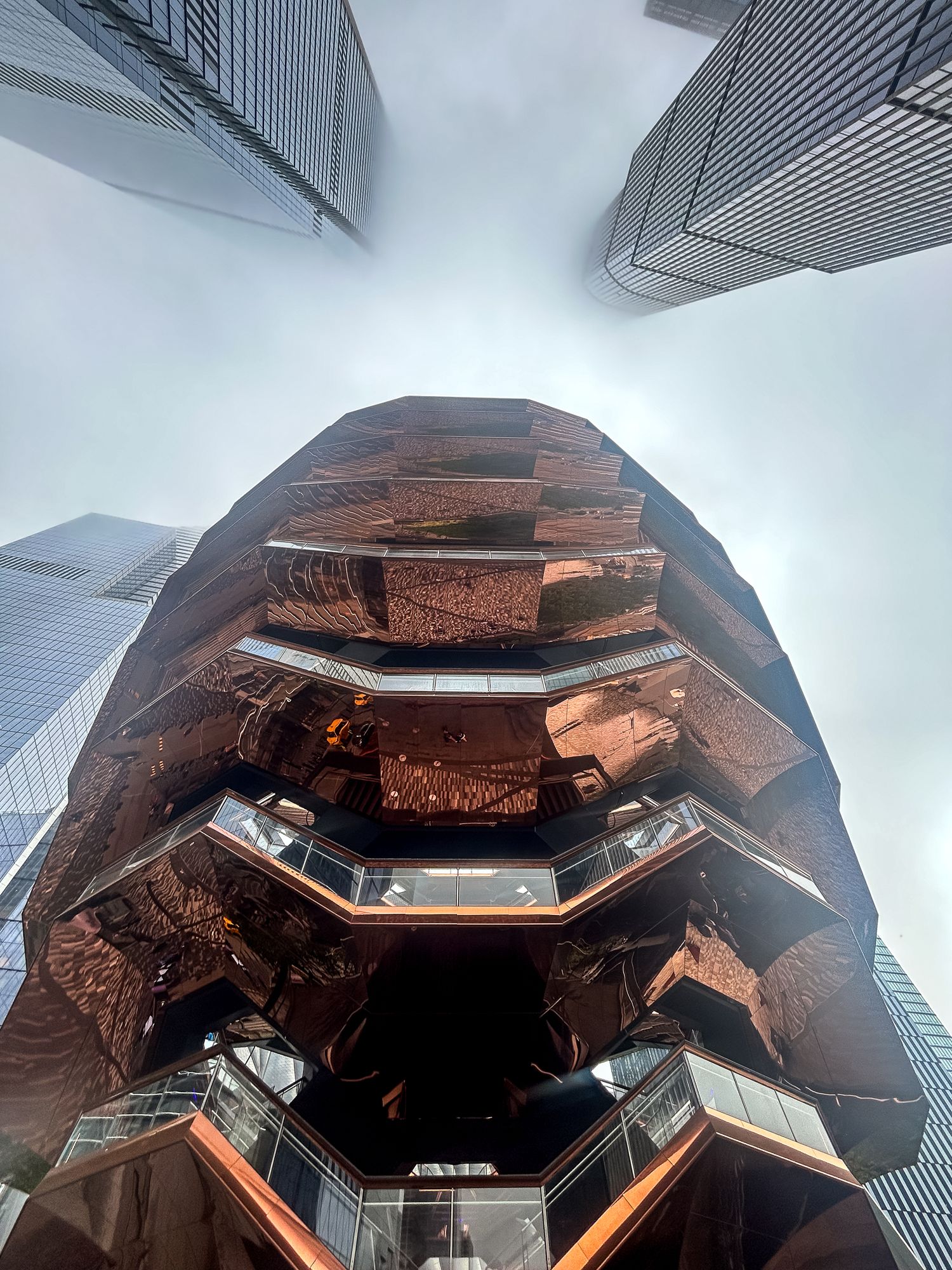 Spiral copper-toned 'Vessel' sculpture with geometric honeycomb pattern of interconnected staircases at Hudson Yards in New York.