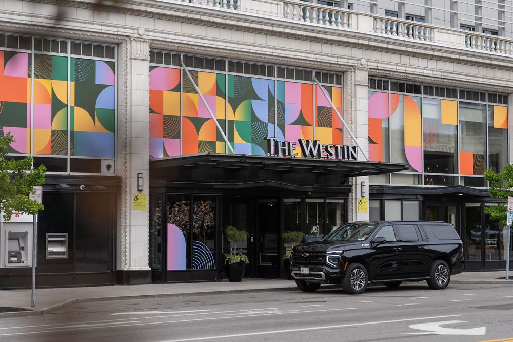 Colorful geometric patterns decorate the exterior walls and windows of The Westin Hotel building along an urban street.