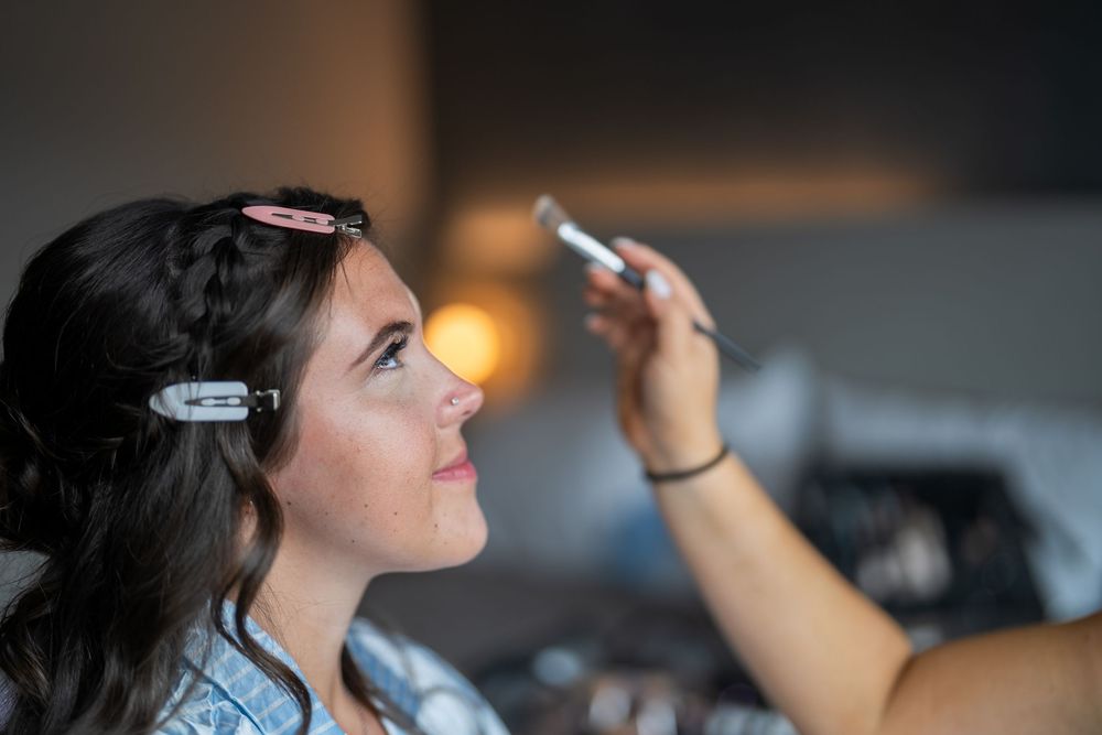 Woman with hair clips gazes upward while holding pen in dimly lit room.