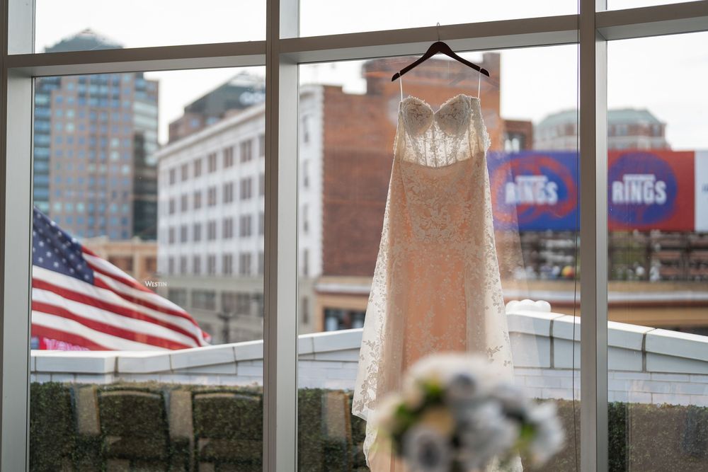 American flag flying in an urban setting with buildings and brick architecture visible through glass windows.