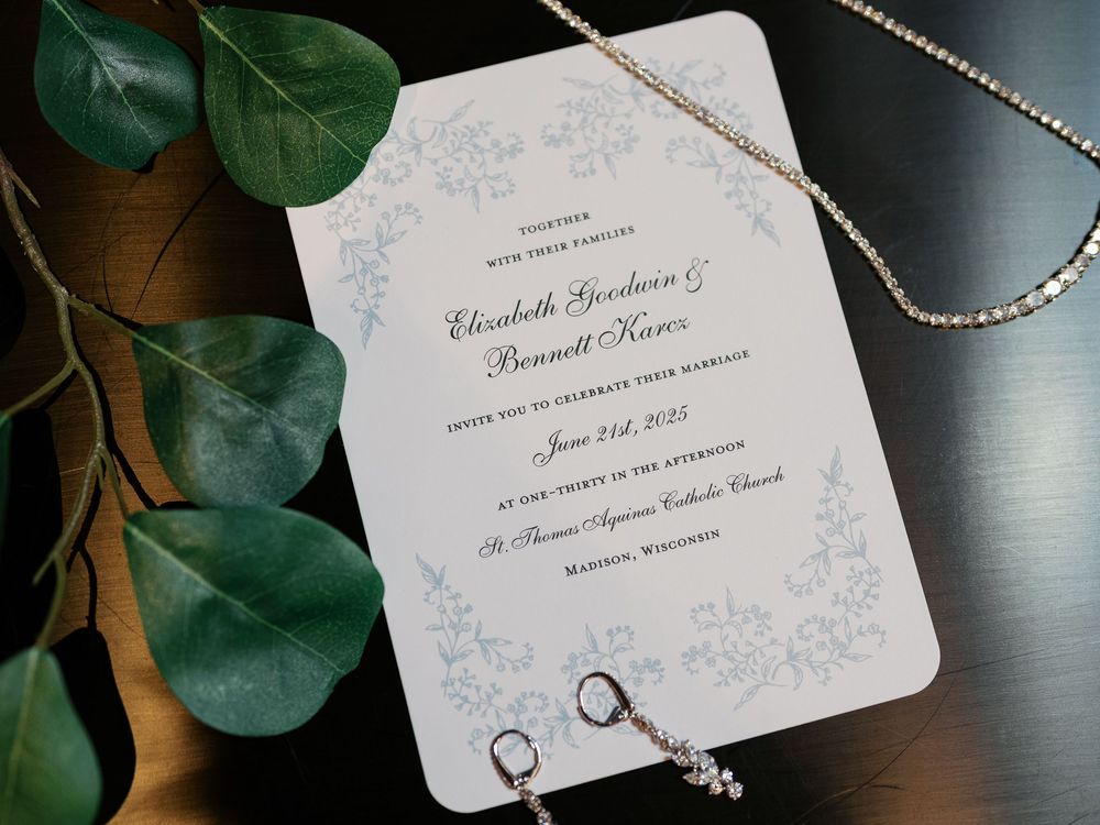 Wedding invitation with eucalyptus leaves and rings captured in an artistic flat lay composition.