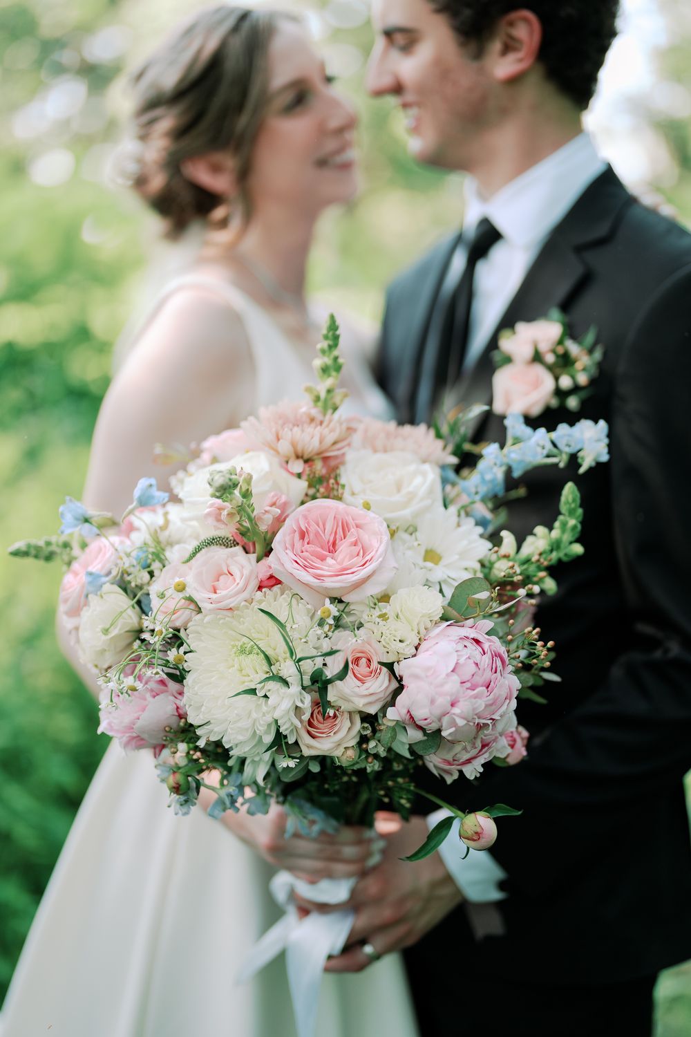 Close up view of an elegant bridal bouquet with pink roses and white flowers during an outdoor wedding.