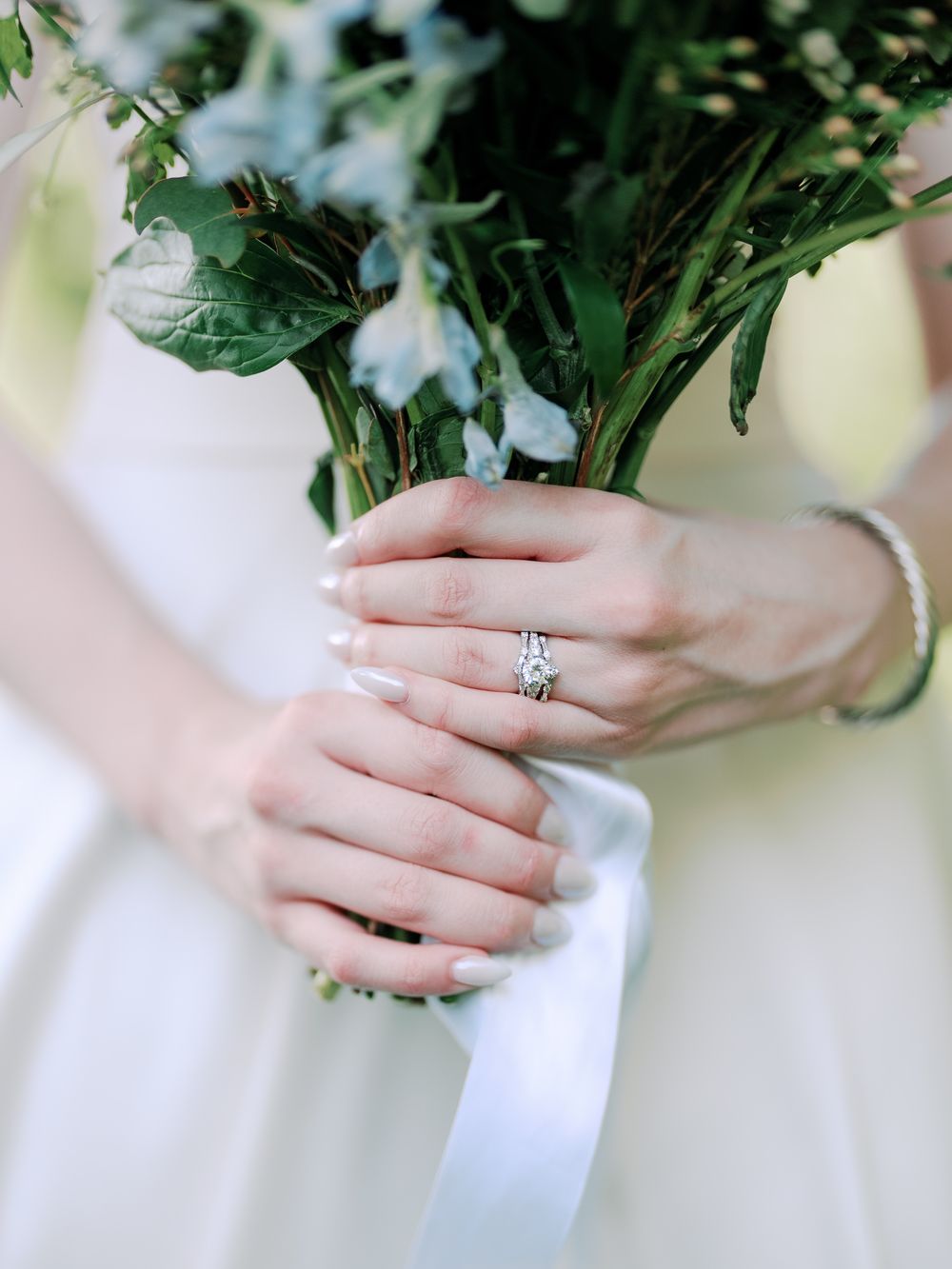 Close-up series showing hands holding white flowers with greenery accents and displaying an engagement ring.