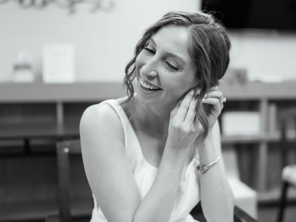 A joyful moment captured in a black and white photograph showing someone laughing while wearing a white sleeveless top.
