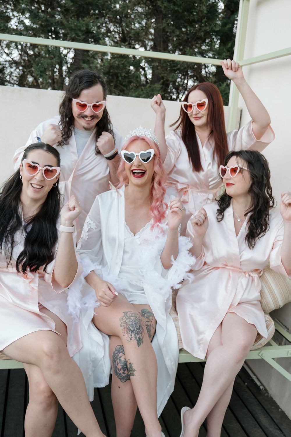 A group in white outfits and sunglasses pose playfully in a sequence of five connected photos on a deck outdoors.