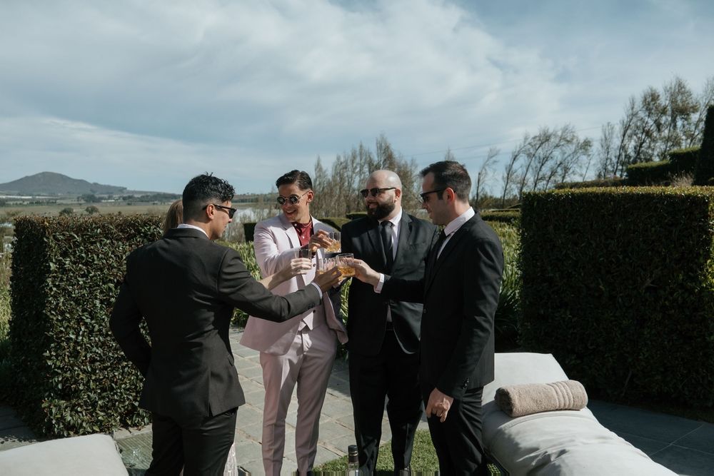 Guests raise their glasses in a celebratory toast during an outdoor garden wedding reception.