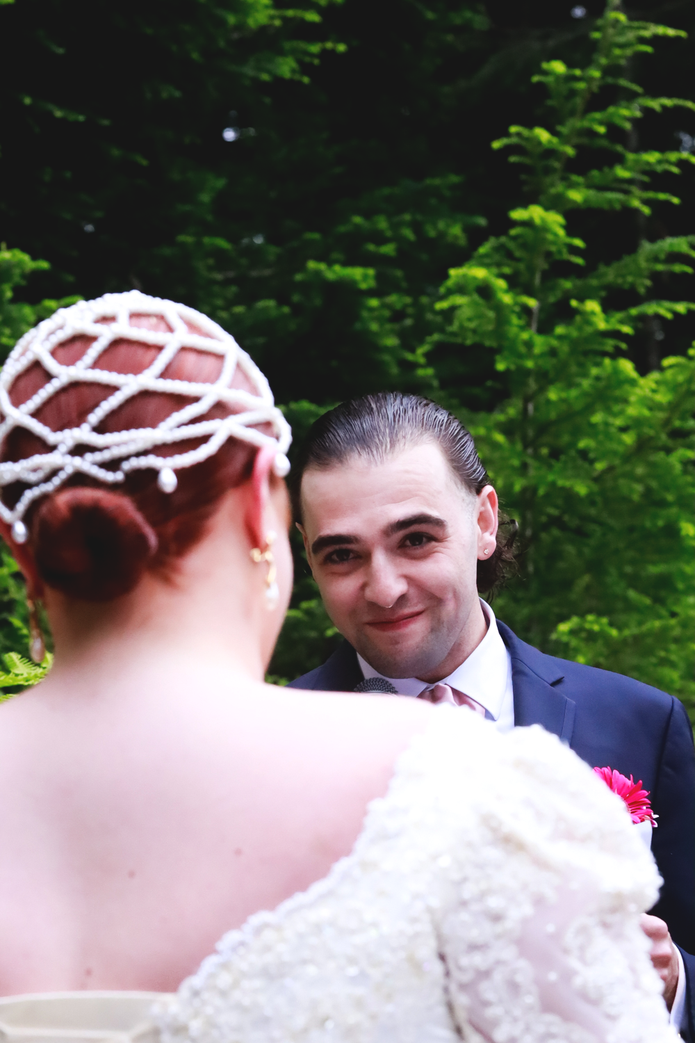 A couple sharing a tender moment during their wedding celebration in a lush green garden setting.