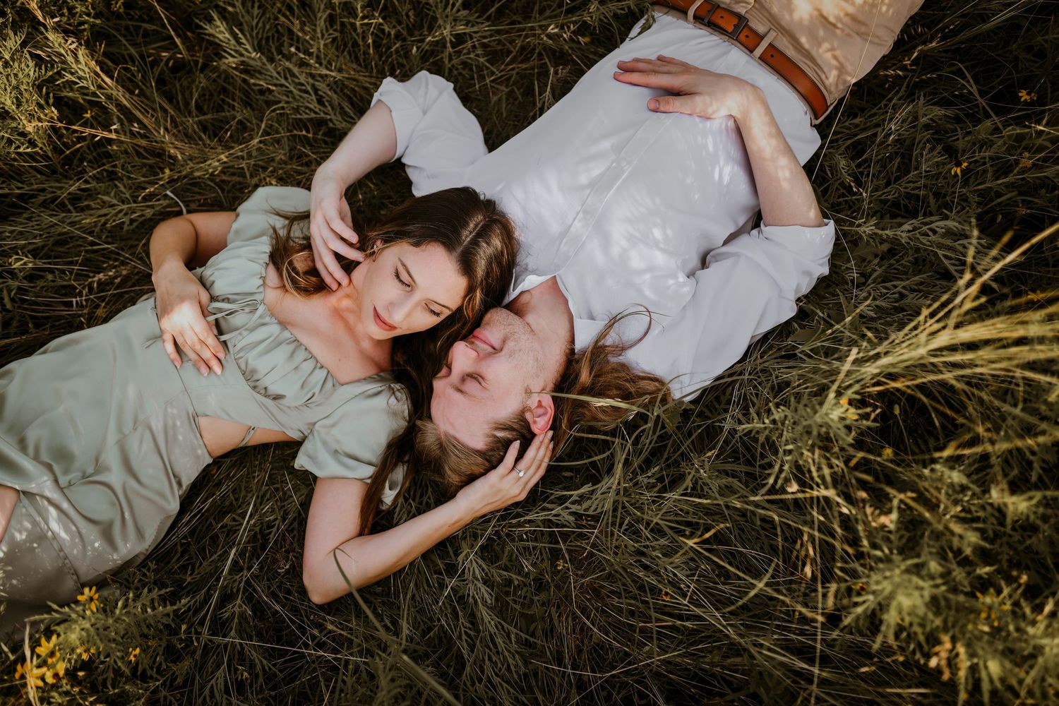 Playful moment of couple laughing during photo shoot in a natural grassland