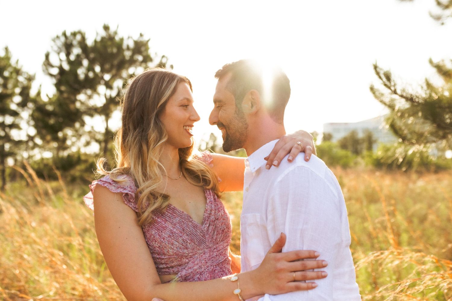 Loving couple embraces in golden wheat field at sunset while enjoying romantic summer evening together.