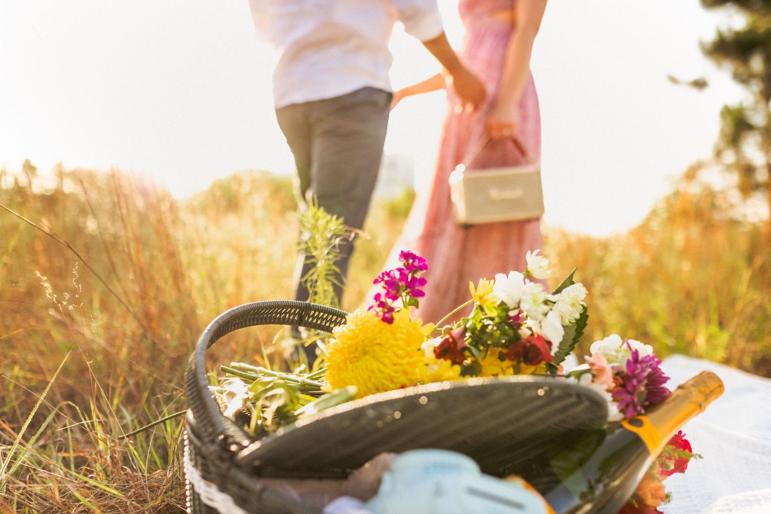 Person wearing boots walks through a wildflower meadow at sunset with warm golden light filtering through.