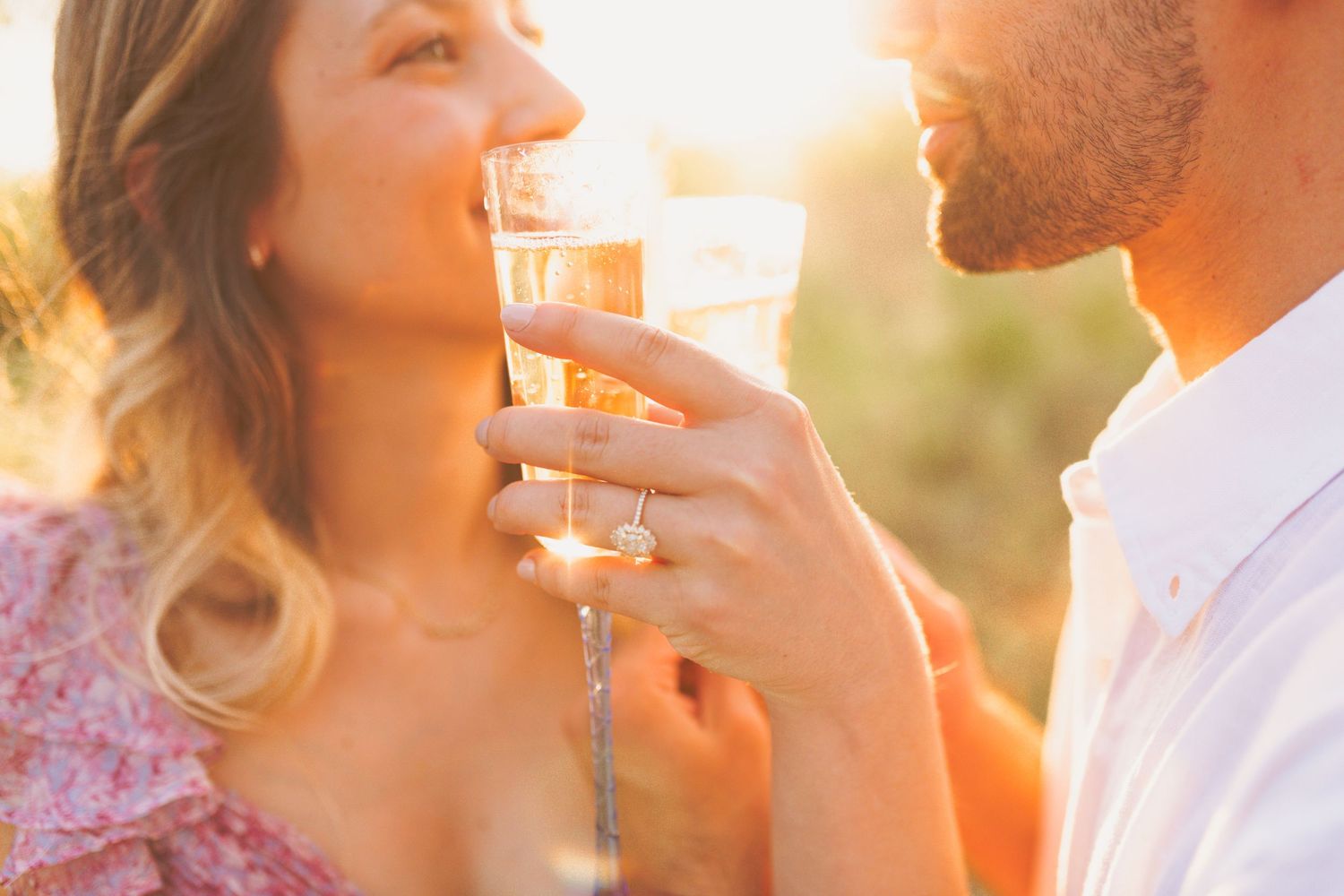 Couple sharing drinks outdoors with wine glasses at sunset creating romantic golden hour atmosphere.