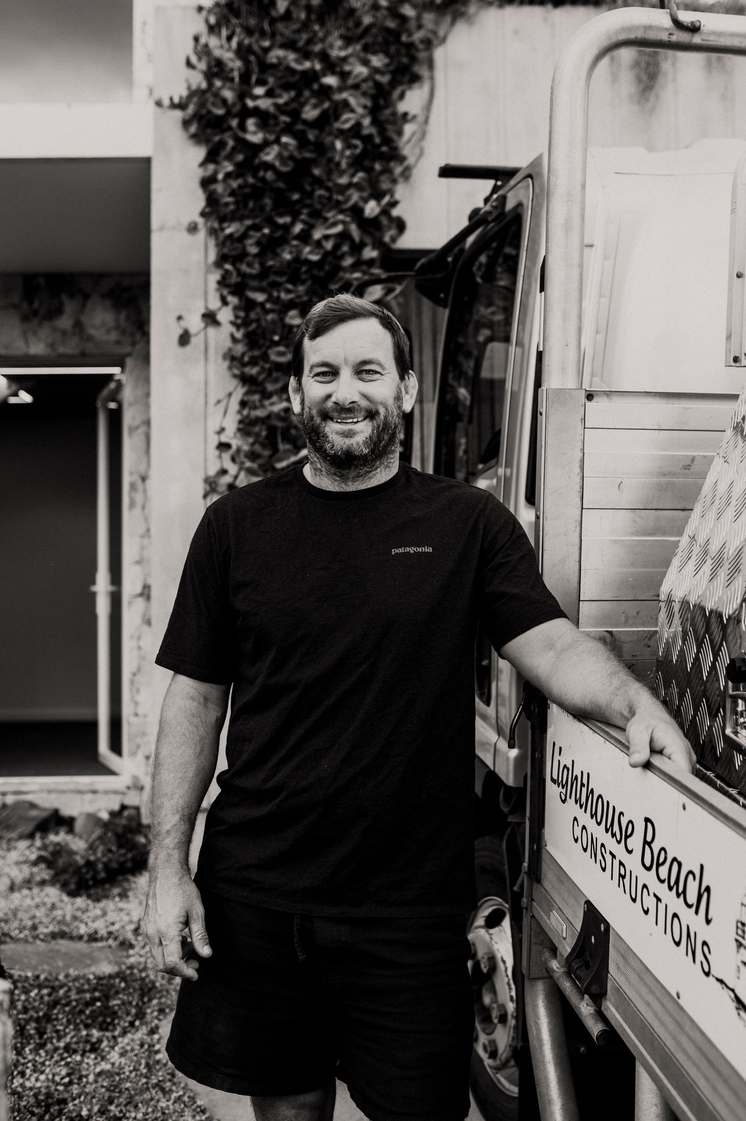 Black and white photo of someone standing next to a delivery truck with 'Beach' visible in partial signage.
