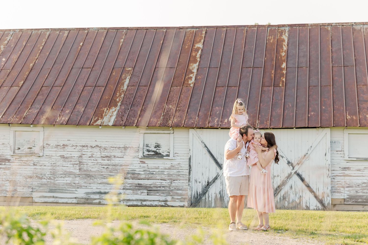 A rustic wooden barn wall serves as a backdrop for a nostalgic summertime photo session.