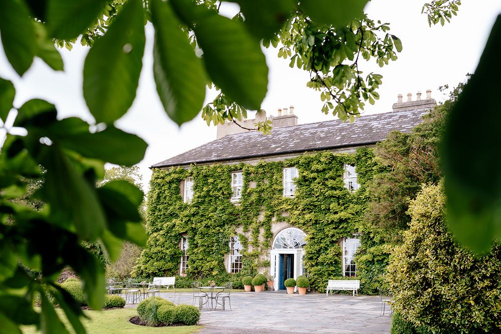 Aerial view of a rustic country estate with stone buildings and lush greenery surrounding the property.