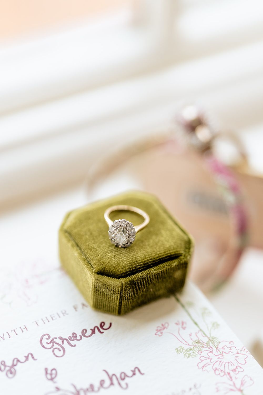 Diamond engagement ring in green velvet box on floral paper.