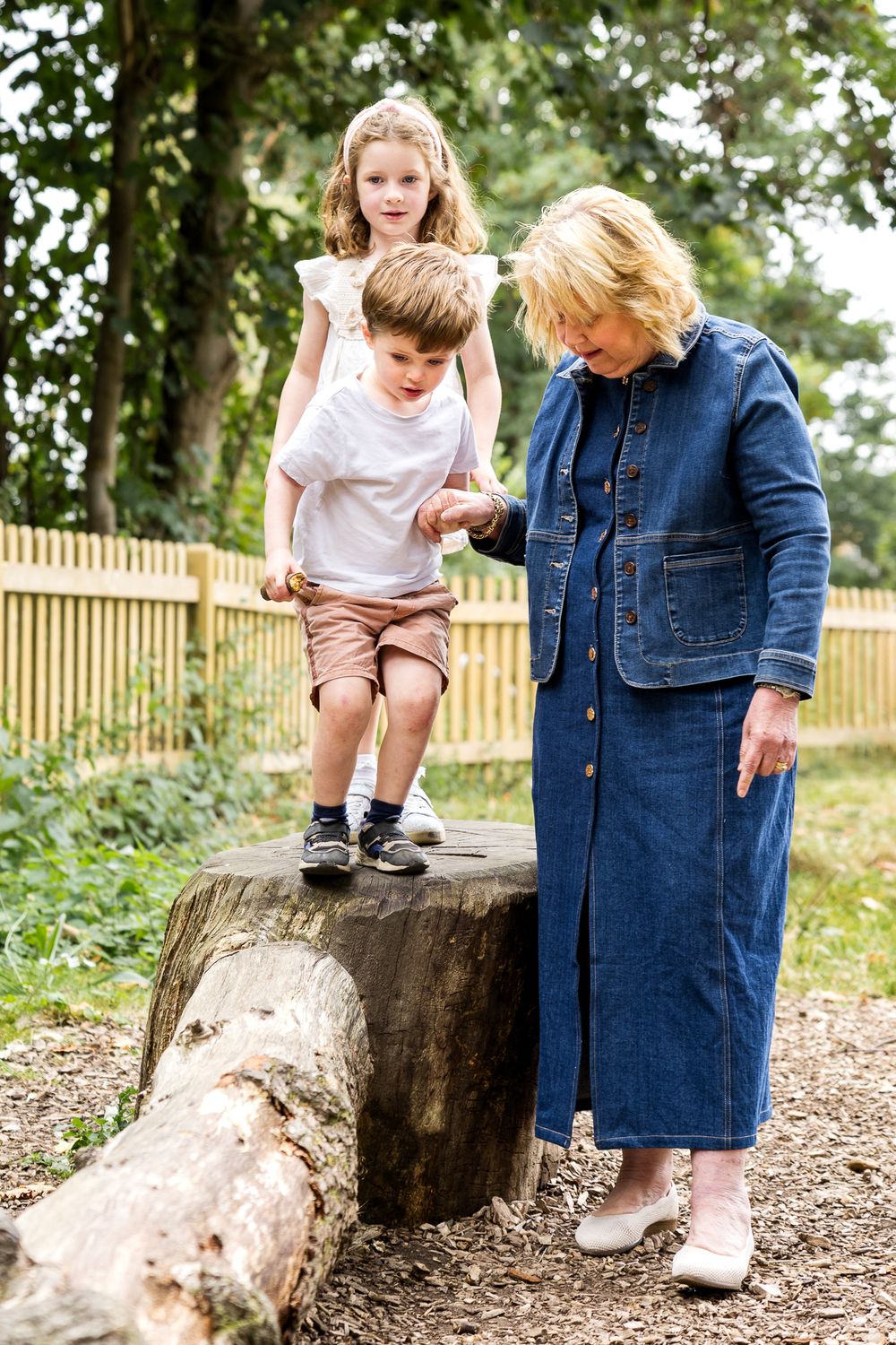 grandma playing with grandkids in wooden playground